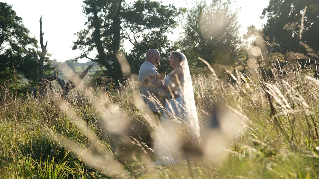 Bride and groom standing together in a meadow at golden hour at Le Petit Chateau